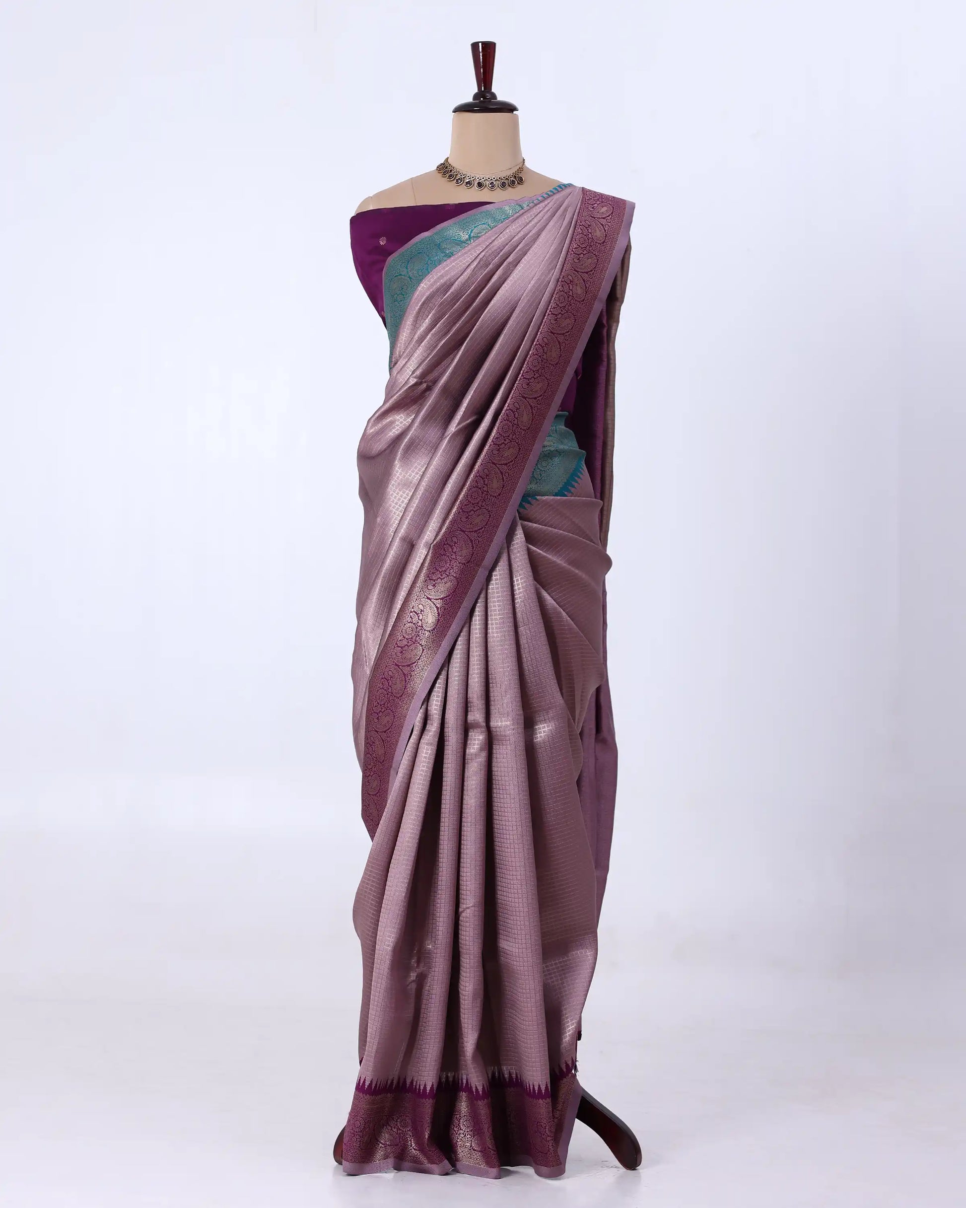 A draped purple saree with a teal-green blouse and a metallic purple border