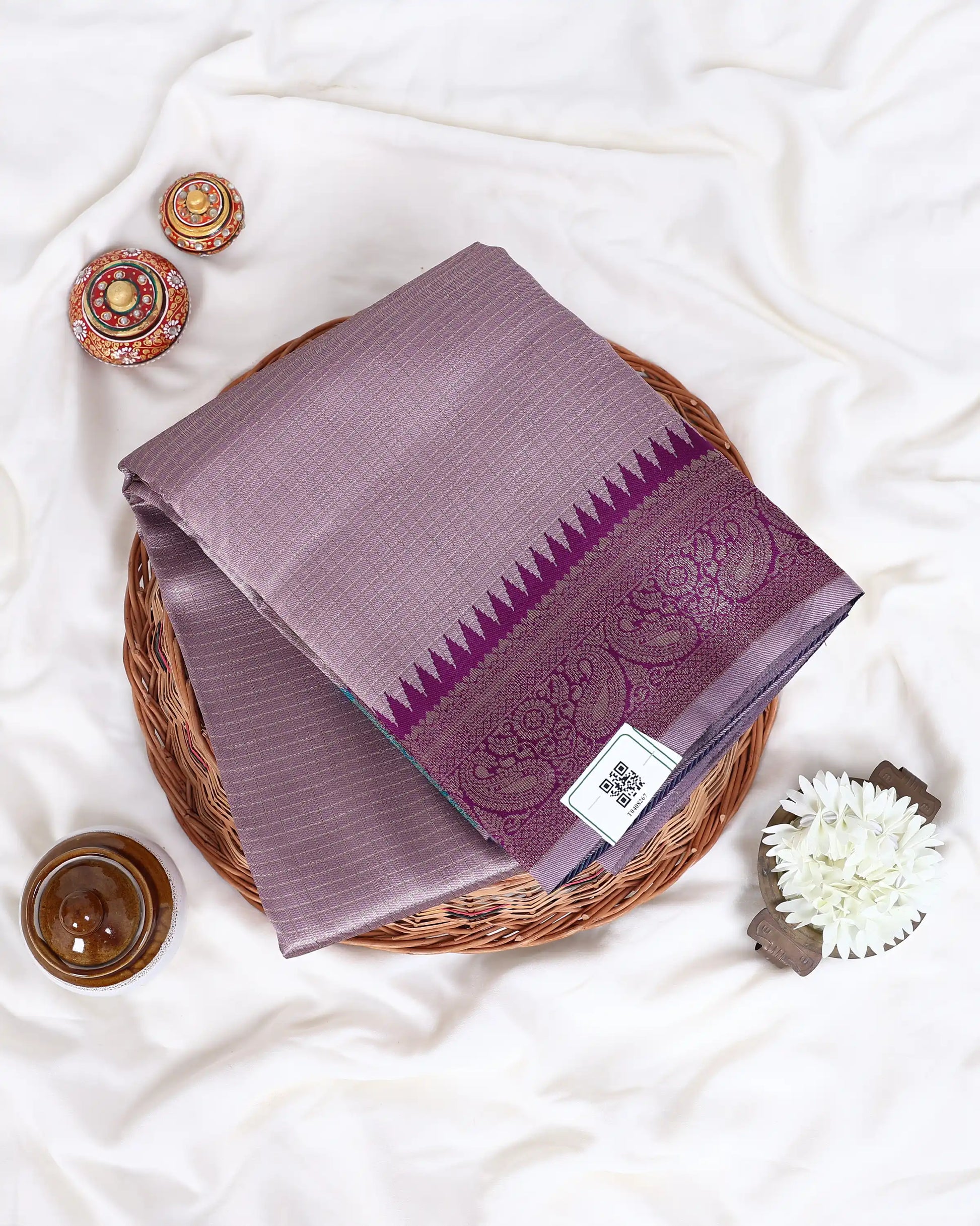 A folded purple silk saree with a detailed brocade border 