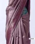 A close-up of a draped sari in a muted mauve-purple color with a wide decorative border featuring metallic floral motifs.