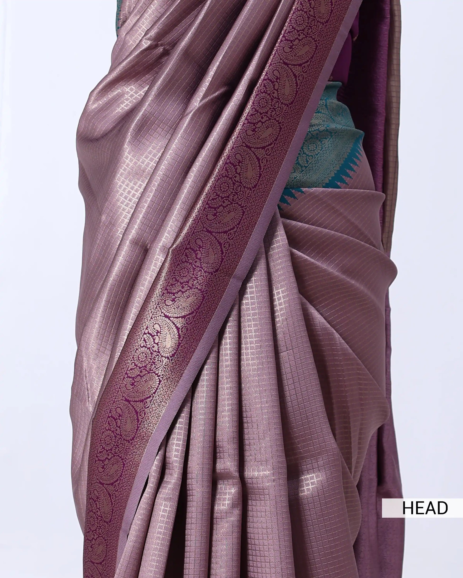 A close-up of a draped sari in a muted mauve-purple color with a wide decorative border featuring metallic floral motifs.
