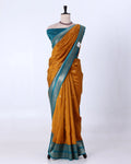 A mustard yellow and teal blue saree  featuring a metallic silver border
