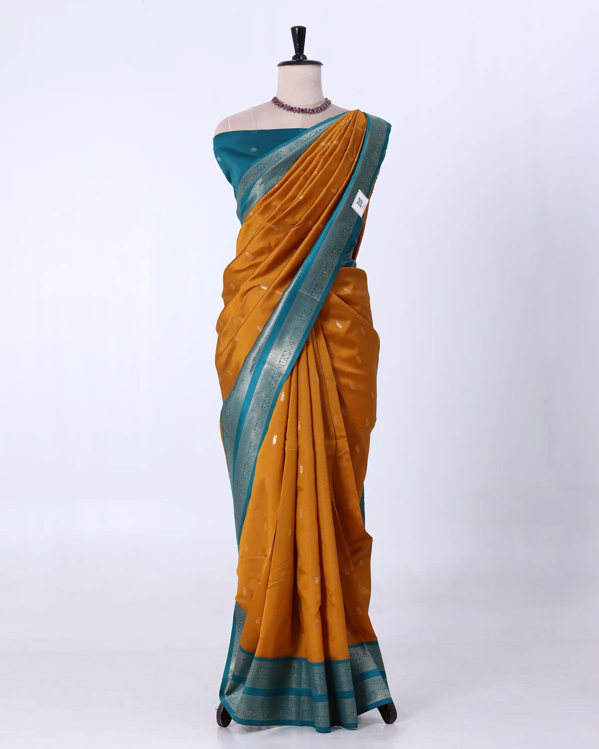 A mustard yellow and teal blue saree  featuring a metallic silver border