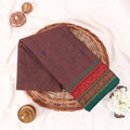 Kanchi Cotton Saree With Brown Weave And Green Maroon Zari Border Neatly Folded On Wicker Basket Top View
