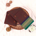 Kanchi Cotton Saree With Green And Gold Zari Border In Brown Tones Folded Flat Lay View With Decor Accents
