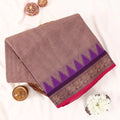 Chettinad cotton saree with subtle brown body purple temple border and zari woven edge folded front view on display.