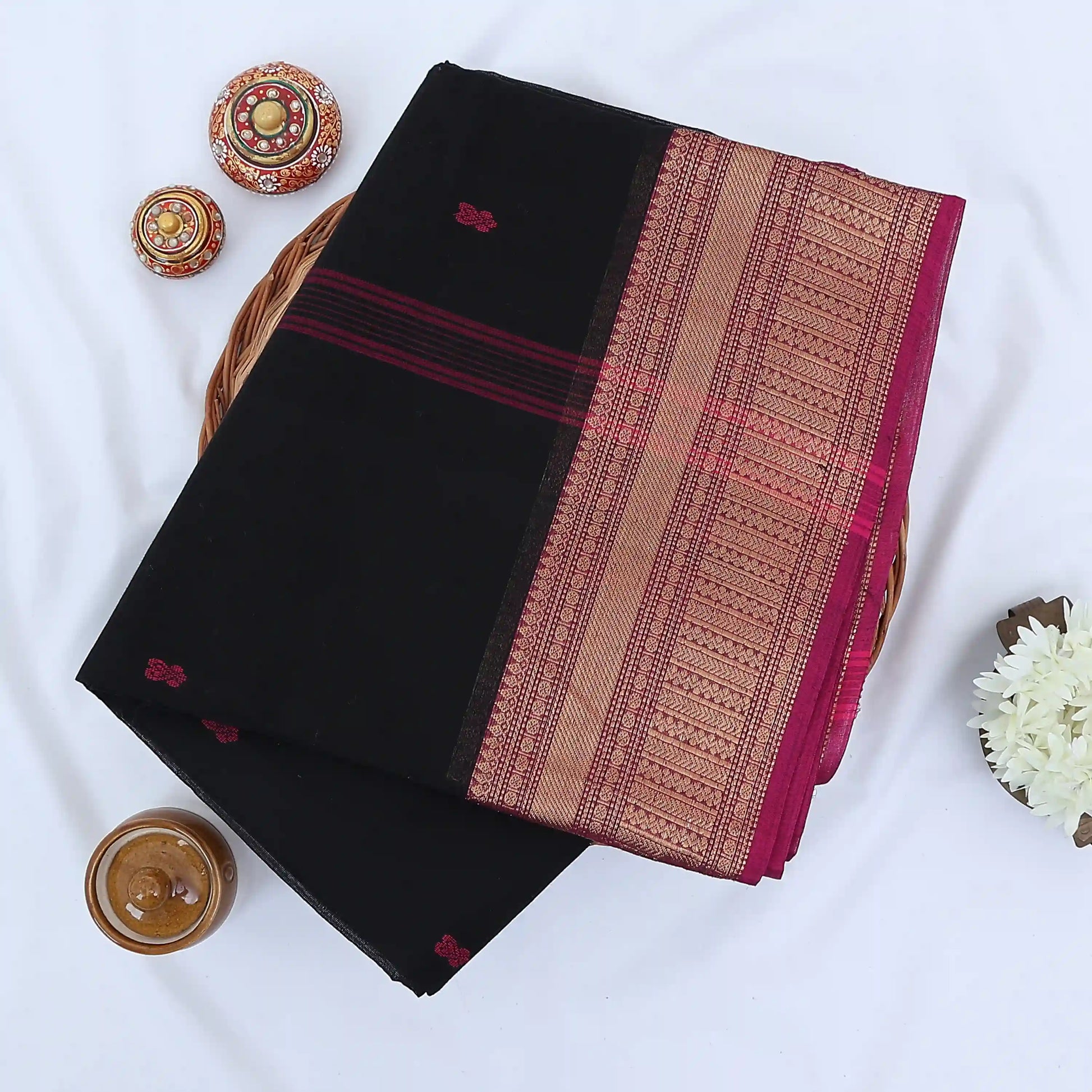 Chettinad cotton saree with red butta motifs and pink zari woven border in black folded top view