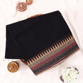 Chettinad cotton saree with solid black body beige temple border and traditional woven zari design folded front view.