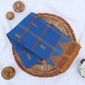 Chettinad cotton saree with blue checked body gold butta motifs and temple border folded flat lay view