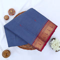 Chettinad cotton saree with blue body and red zari border folded top view with woven motifs.