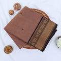 Chettinad cotton saree with brown body black buttas and gold zari border folded in a basket top view.