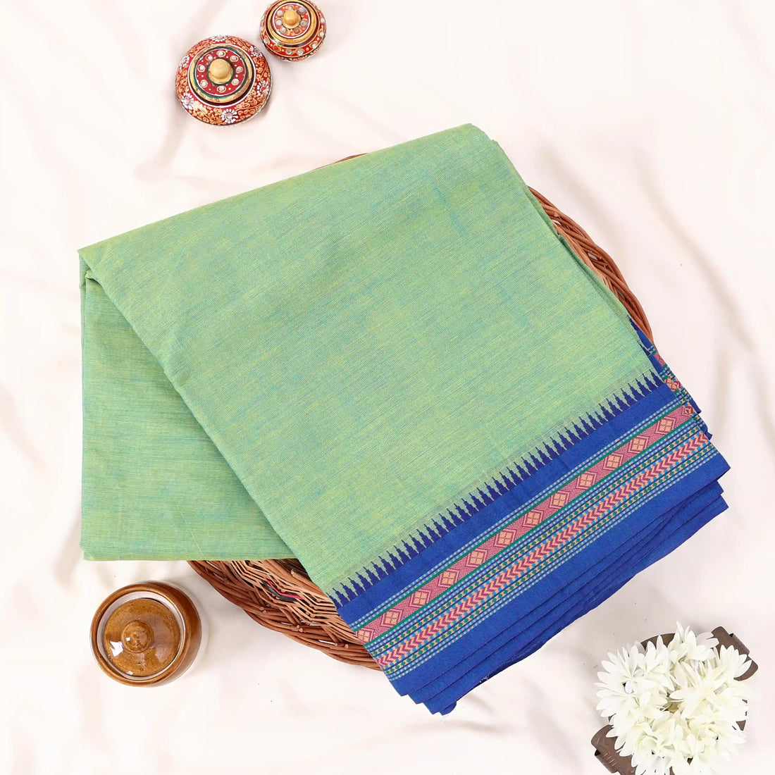 Chettinad cotton saree with plain body and temple border in green and blue folded top view