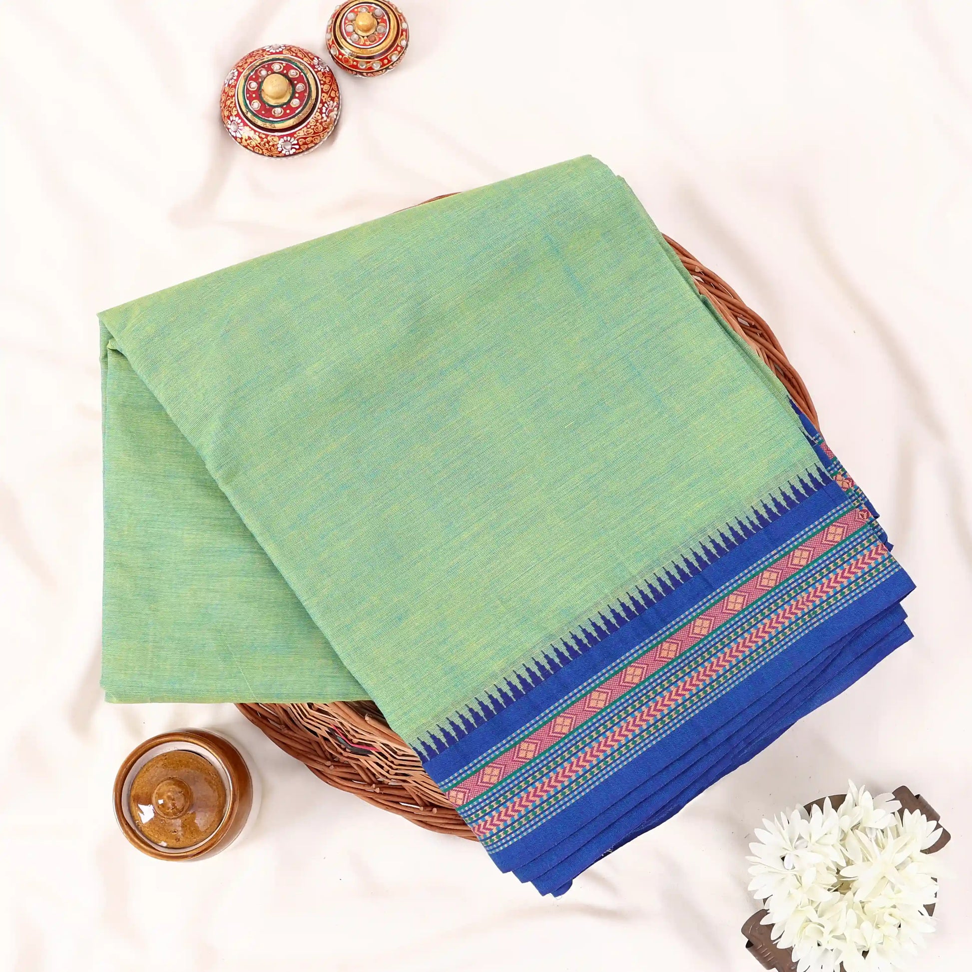 Chettinad cotton saree with plain body and temple border in green and blue folded top view