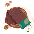 Chettinad cotton saree with elephant zari border and checked body in maroon and green folded top view.