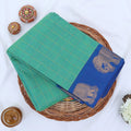 Chettinad cotton saree with elephant zari border and checked body in green and blue folded top view.