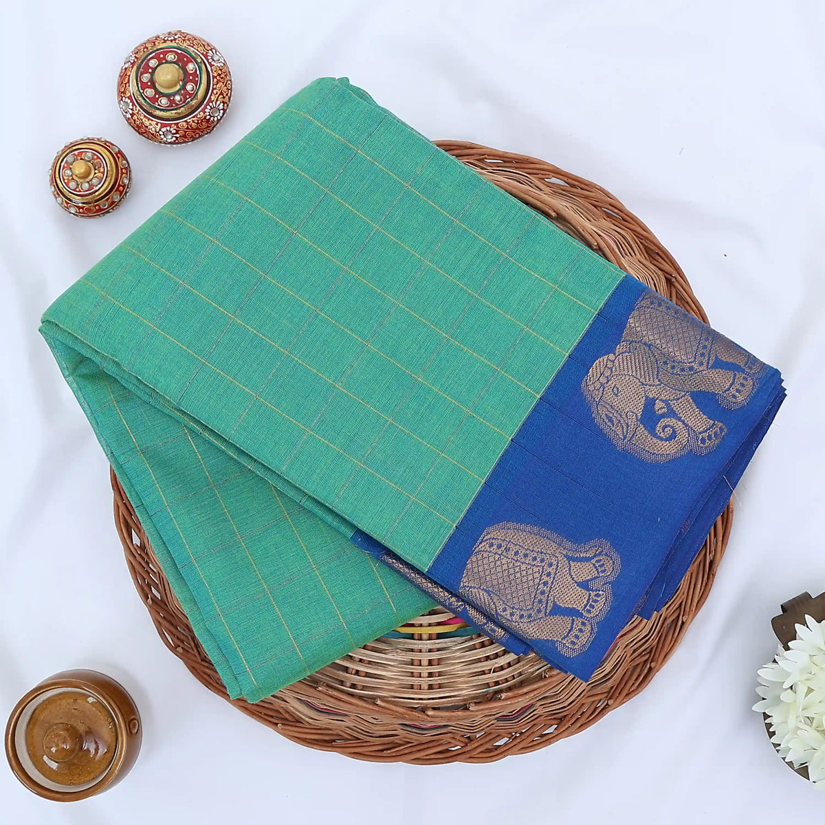 Chettinad cotton saree with elephant zari border and checked body in green and blue folded top view.