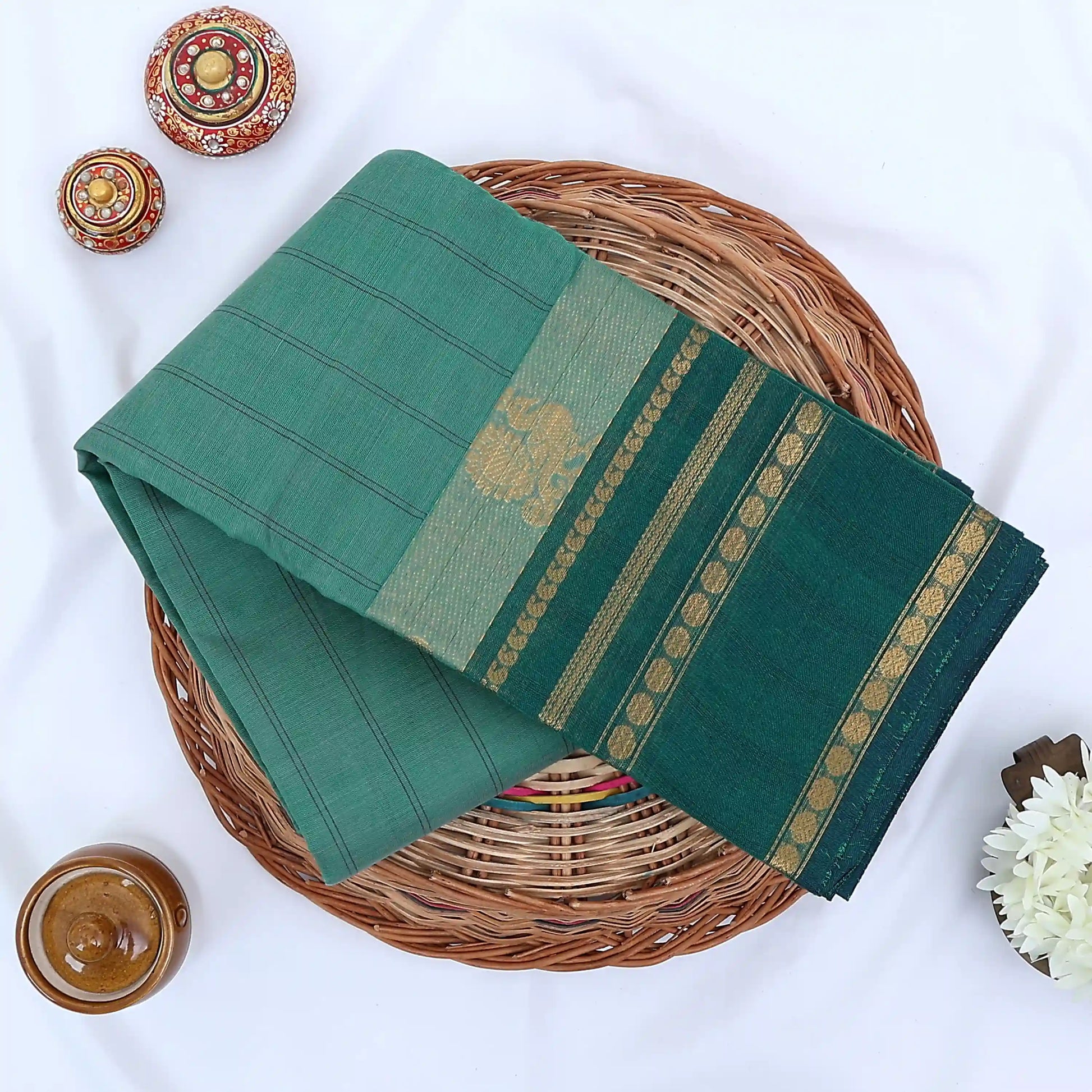Chettinad cotton saree with sea green striped body dark green zari border and peacock motif folded flat lay view