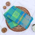 Chettinad cotton saree with green and blue checked body silver floral zari border folded flat lay view