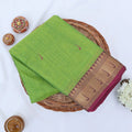 Chettinad cotton saree with light green body and pink zari border folded top view with woven motifs.