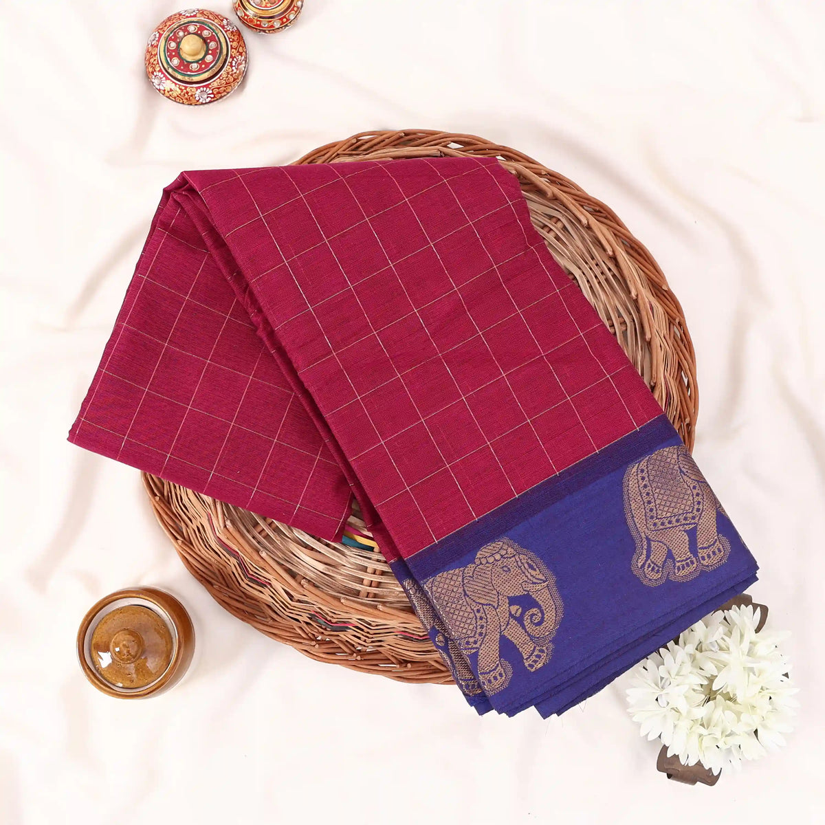 Chettinad cotton saree with elephant zari border and checked body in maroon and blue folded top view.
