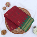 Chettinad cotton saree with maroon checked body green temple zari border and butta motifs folded flat lay view