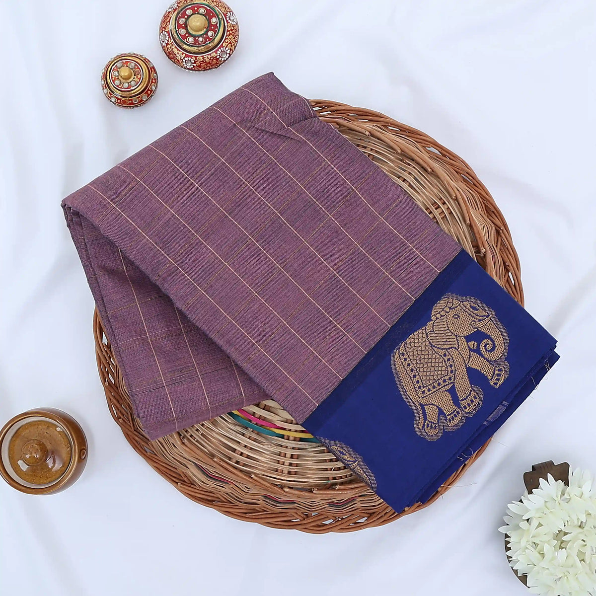 Chettinad cotton saree with elephant zari border and checked body in onion Pink and blue folded top view.