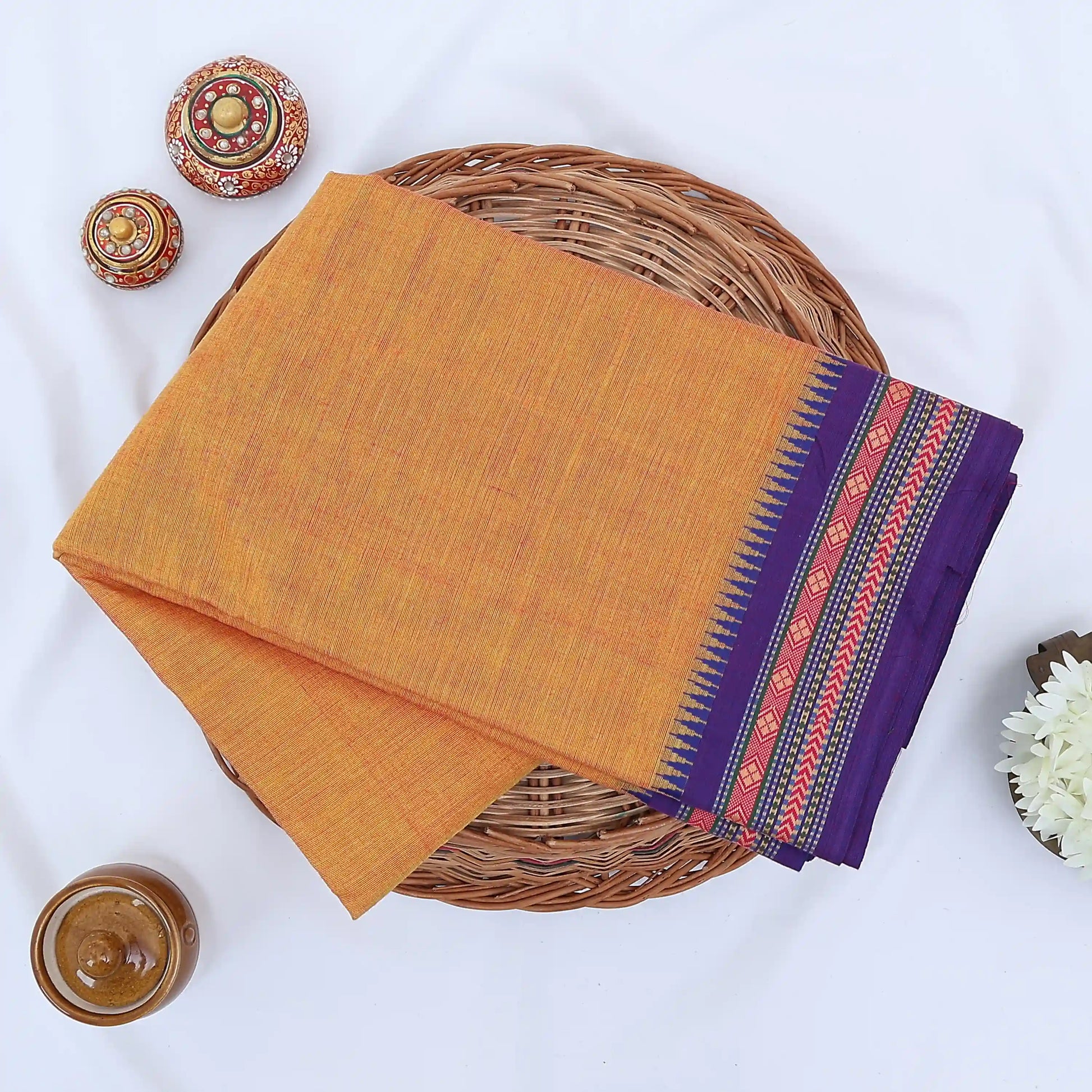 Chettinad cotton saree with plain body and temple border in orange and purple folded top view