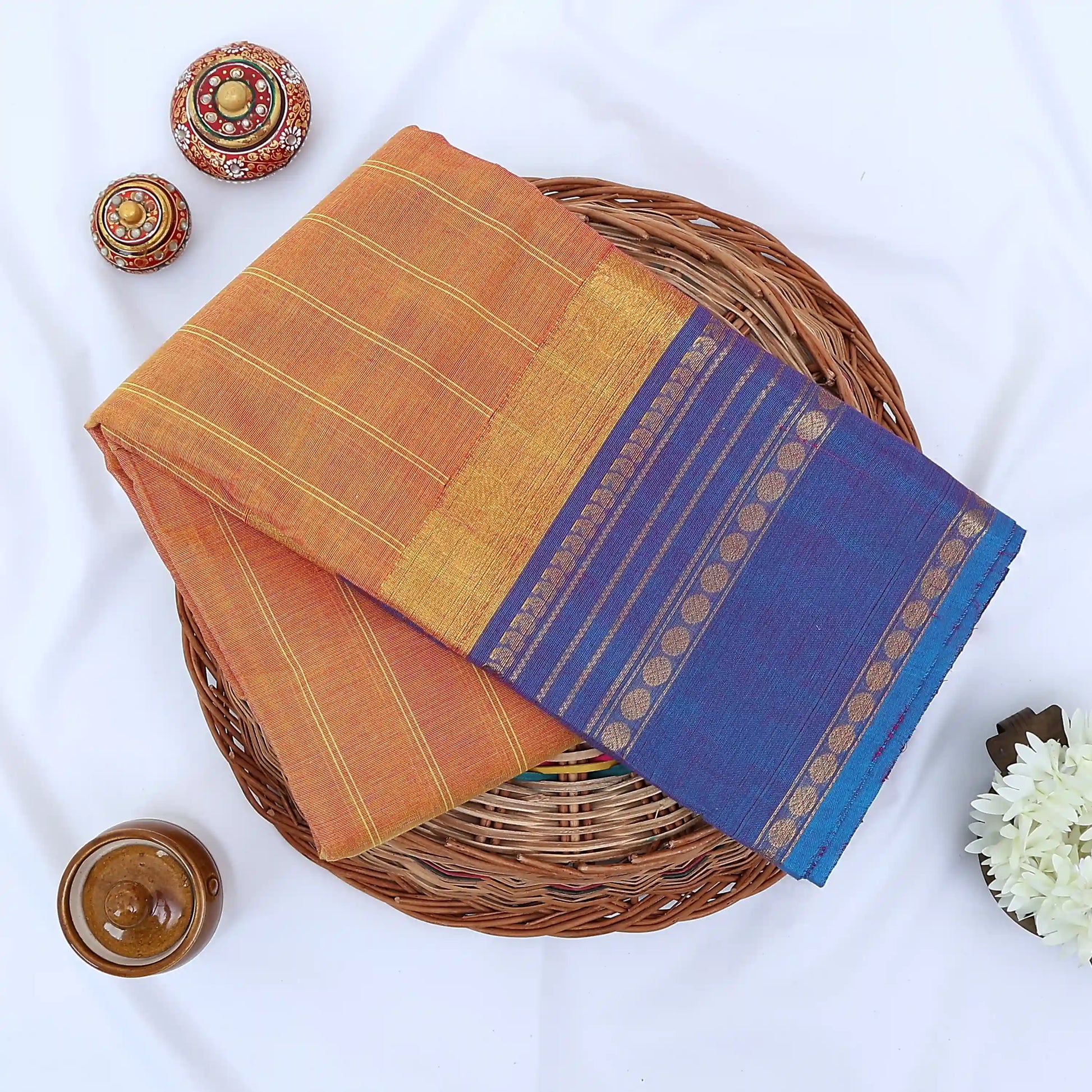 Chettinad cotton saree with orange striped body purple zari border and peacock motifs folded flat lay view
