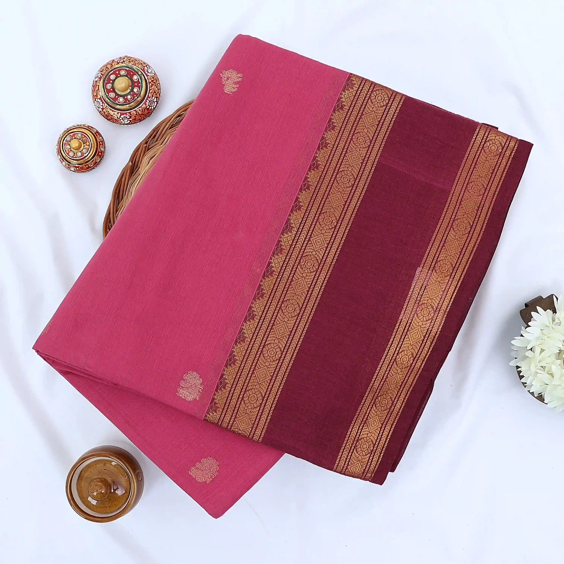 Chettinad cotton saree with zari butta motifs and maroon zari woven border in pink folded top view