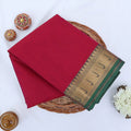 Chettinad cotton saree with pink body and green zari border folded top view with woven motifs.