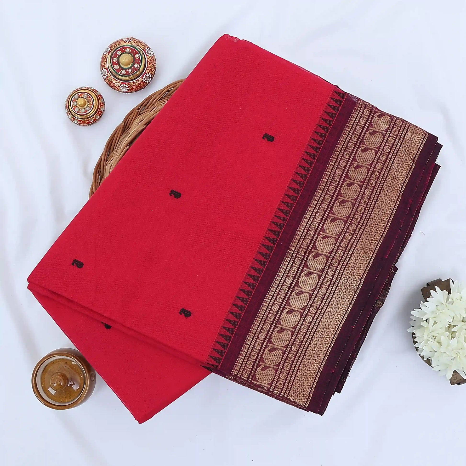 Chettinad cotton saree with plain pink body black buttas and maroon zari woven border folded top view