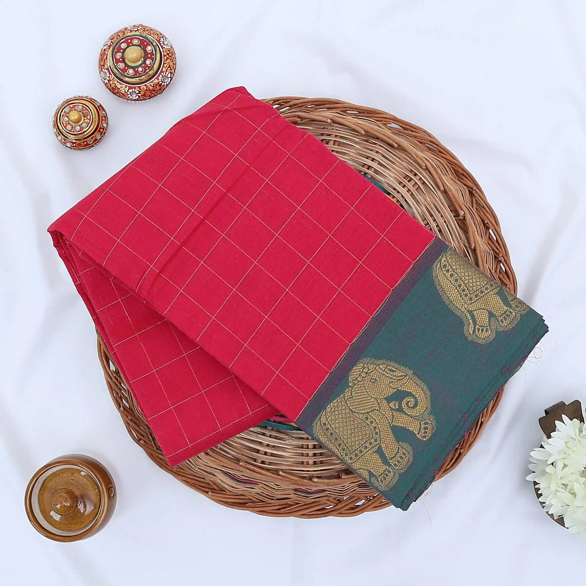 Chettinad cotton saree with elephant zari border and checked body in pink and blue folded top view.