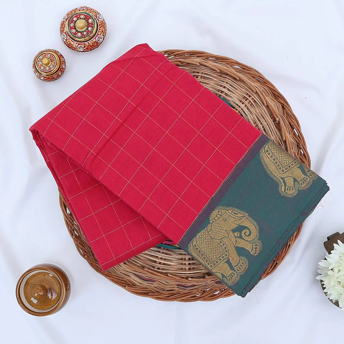 Chettinad cotton saree with elephant zari border and checked body in pink and blue folded top view.