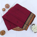 Chettinad cotton saree with purple body black buttas and black peacock zari border folded in a basket top view.