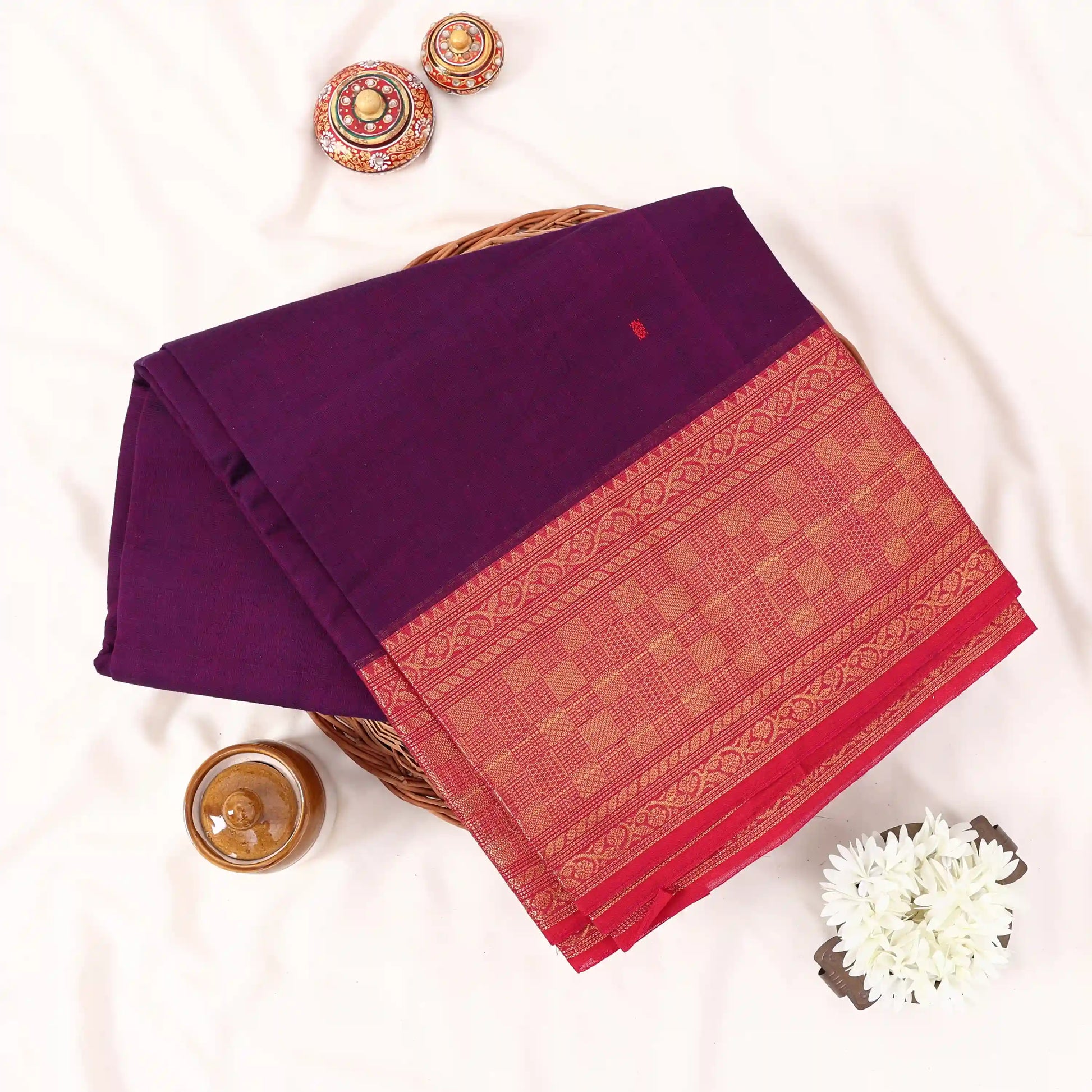 Chettinad cotton saree with plain purple body checked zari border and woven butta motifs folded top view.