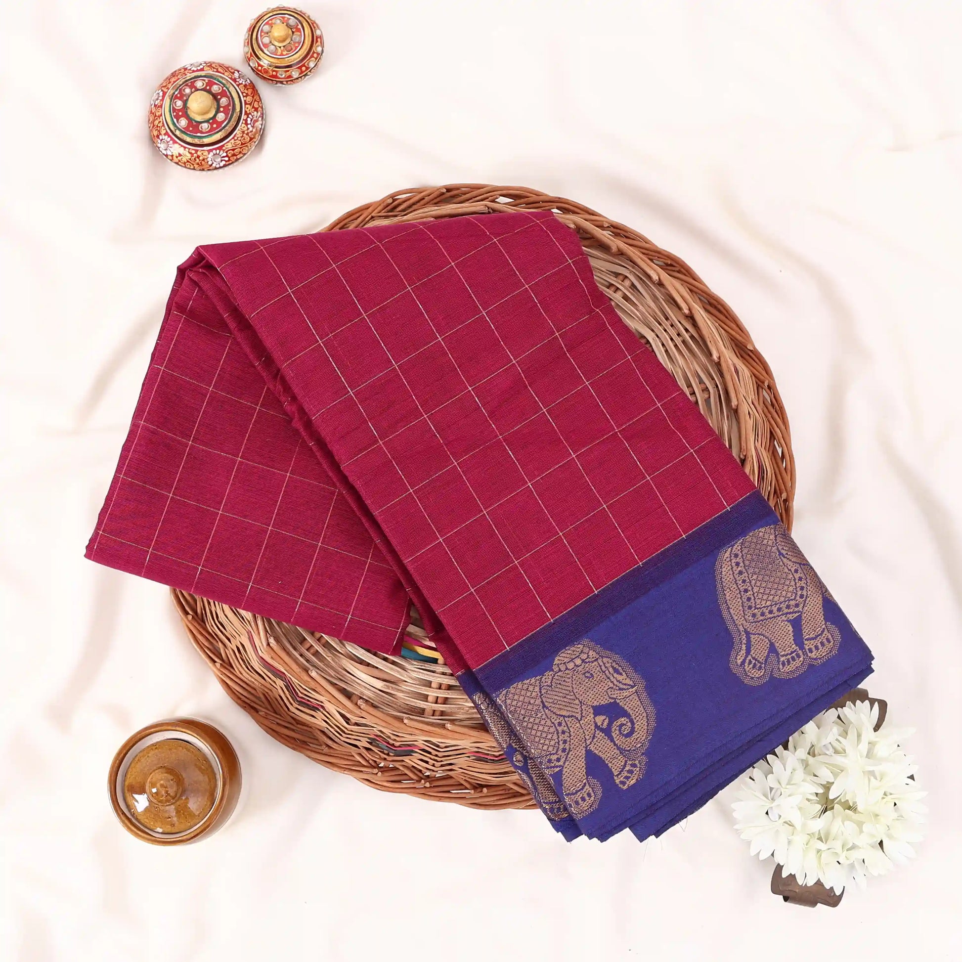 Chettinad cotton saree with elephant zari border and checked body in purple and blue folded top view.
