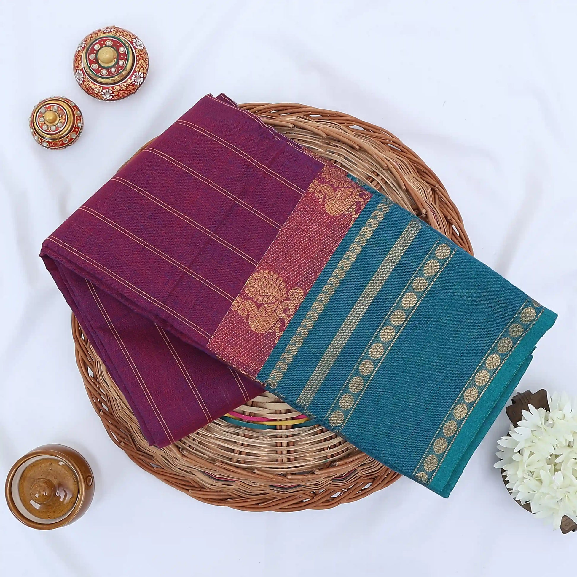 Chettinad cotton saree with purple striped body teal zari border and peacock motifs folded flat lay view