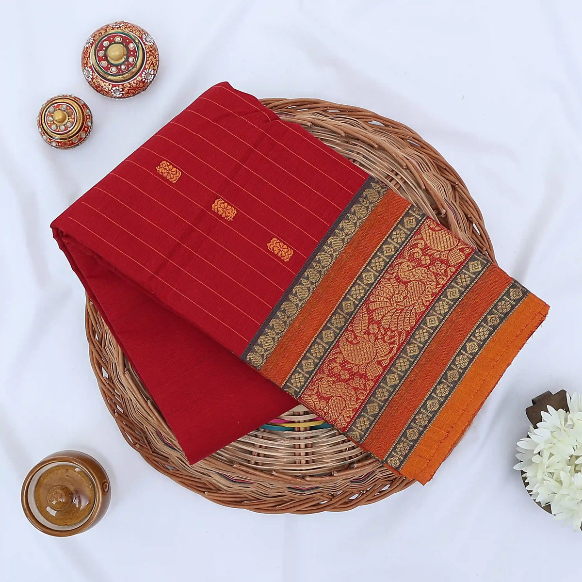 Chettinad cotton saree with zari floral butta striped body peacock border in red folded top view