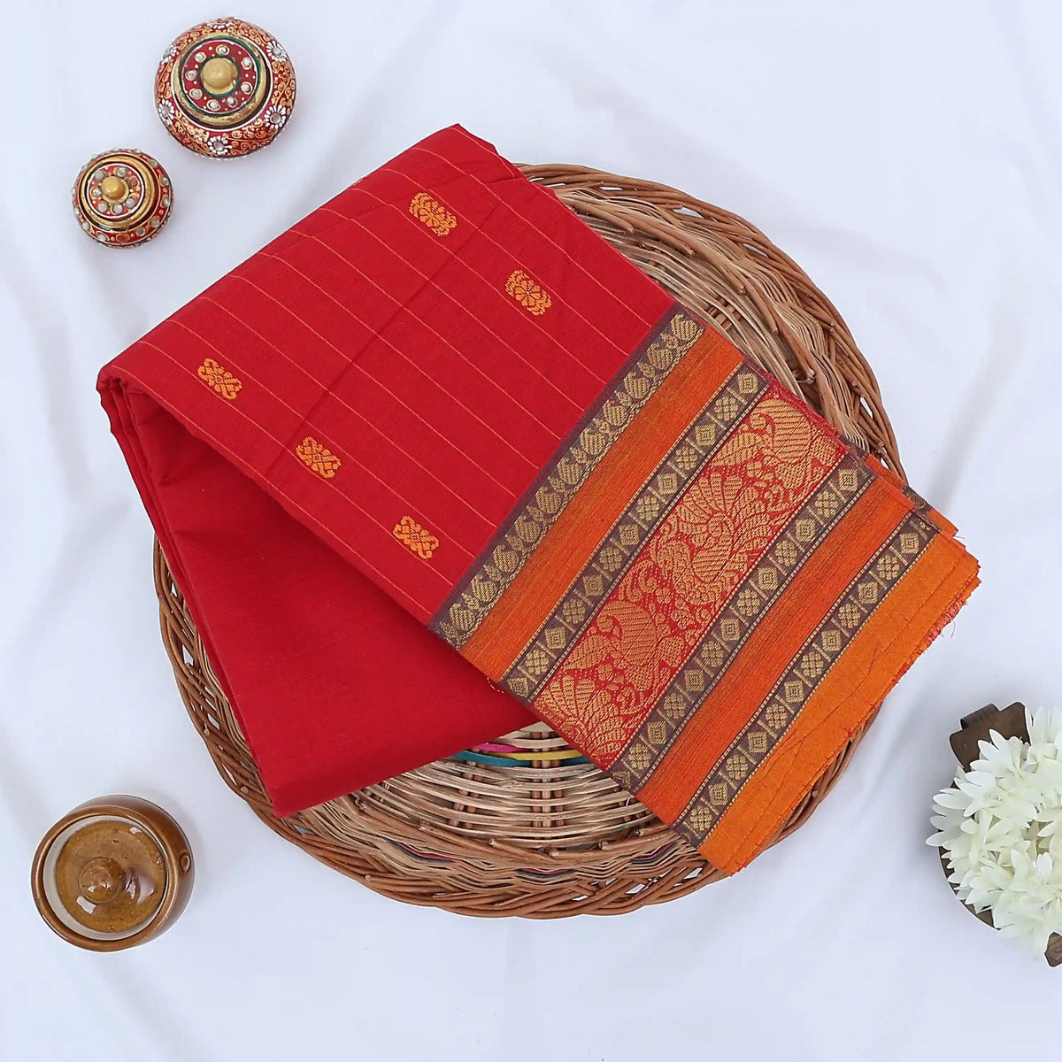 Chettinad cotton saree with zari floral butta striped body peacock border in light red folded top view
