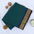Chettinad cotton saree with plain teal green body gold zari floral border folded top view on wicker basket