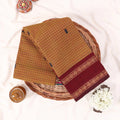 Chettinad cotton saree with yellow checked pattern maroon zari border folded flat in a basket top view.
