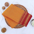 Chettinad cotton saree with plain body and red zari woven border in orange folded top view