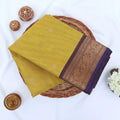 Chettinad cotton saree with zari buttas and floral zari border in yellow and purple folded top view.