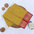 Chettinad cotton saree with mustard yellow body and maroon zari border folded top view with woven motifs.