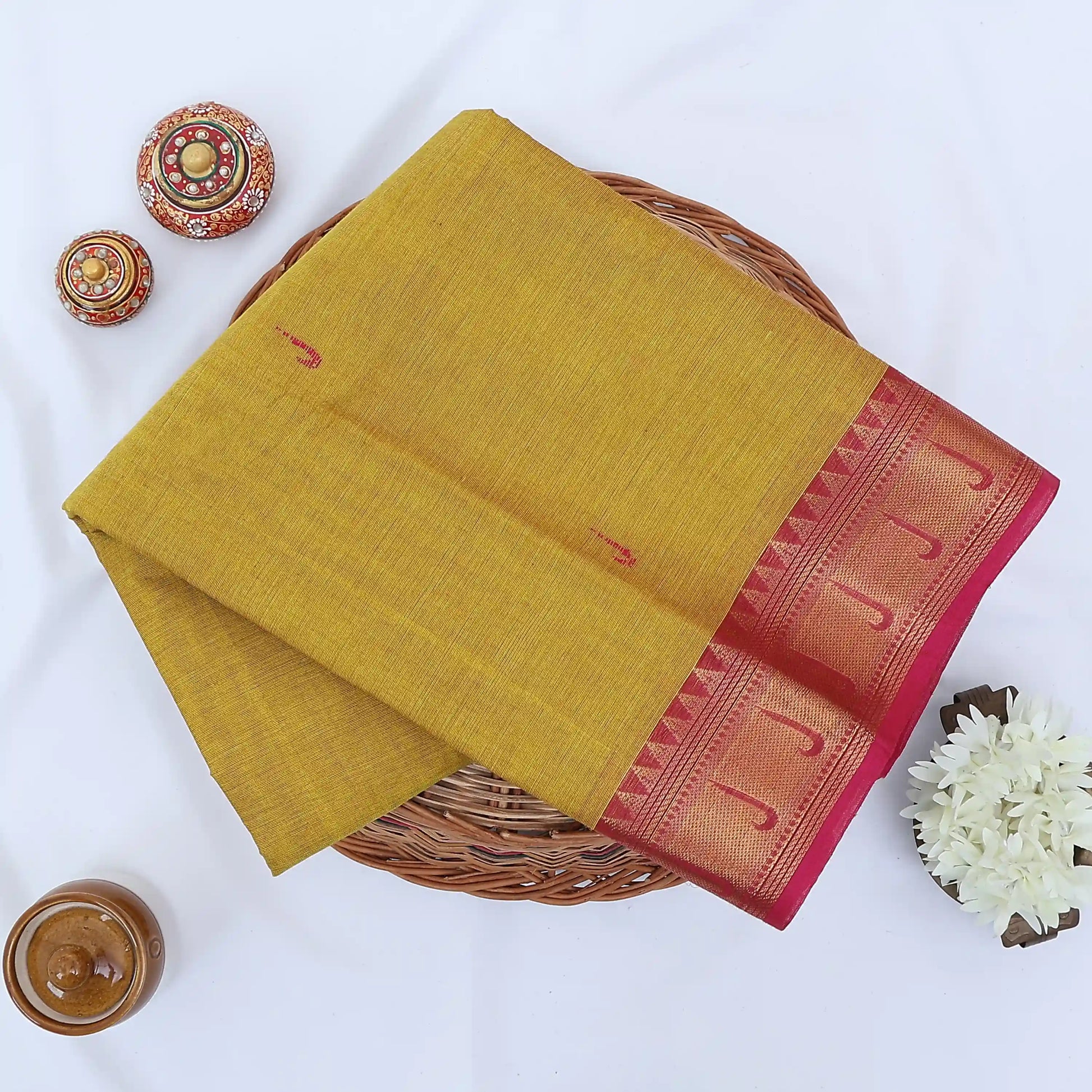Chettinad cotton saree with mustard yellow body and maroon zari border folded top view with woven motifs.