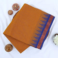 Chettinad cotton saree with plain mustard yellow body blue temple border folded top view on wicker basket