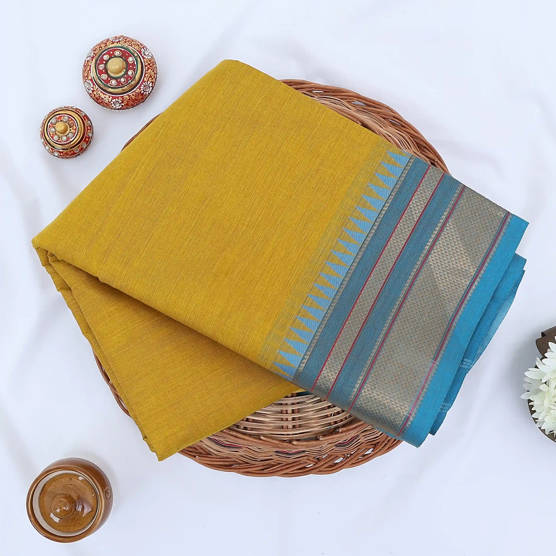 Chettinad cotton saree with plain body and temple zari woven border in yellow folded top view