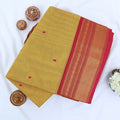 Chettinad cotton saree with red butta motifs and zari woven border in mustard yellow folded top view