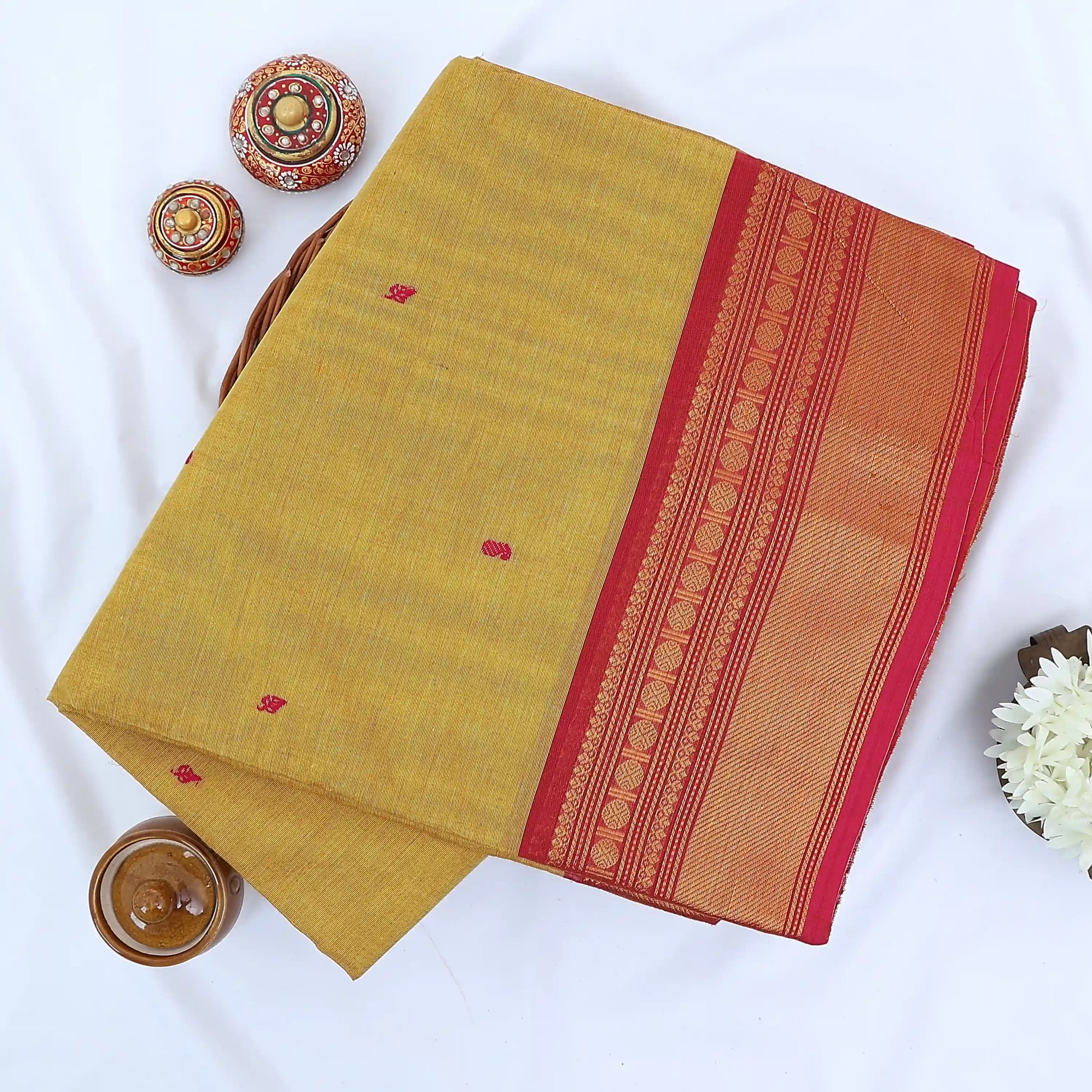 Chettinad cotton saree with red butta motifs and zari woven border in mustard yellow folded top view