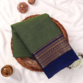 Kanchi Cotton Saree With Green Body And Royal Blue Zari Border Folded Flat Lay View On Wicker Tray
