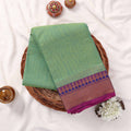 Kanchi Cotton Saree In Light Green With Purple And Gold Zari Border Folded Display Top View With Decorative Accents
